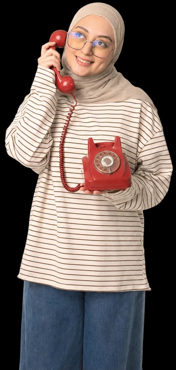 Nada Alshikh smiling on a red rotary telephone
